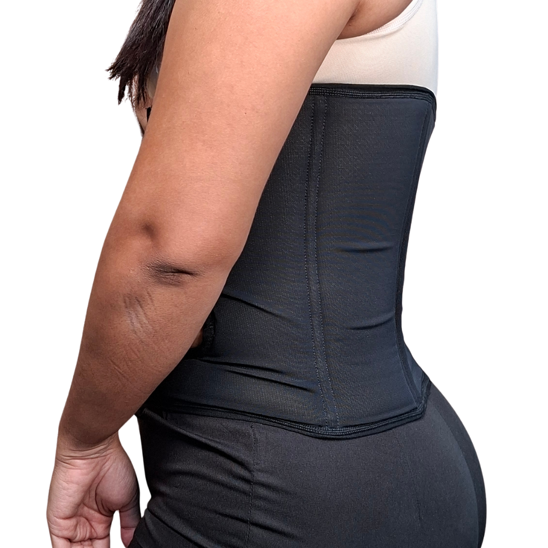 Persona usando una banda abdominal elástica de color negro diseñada para colostomía, con una apertura circular reforzada en el lateral izquierdo para la bolsa de estoma y cierre de velcro frontal.