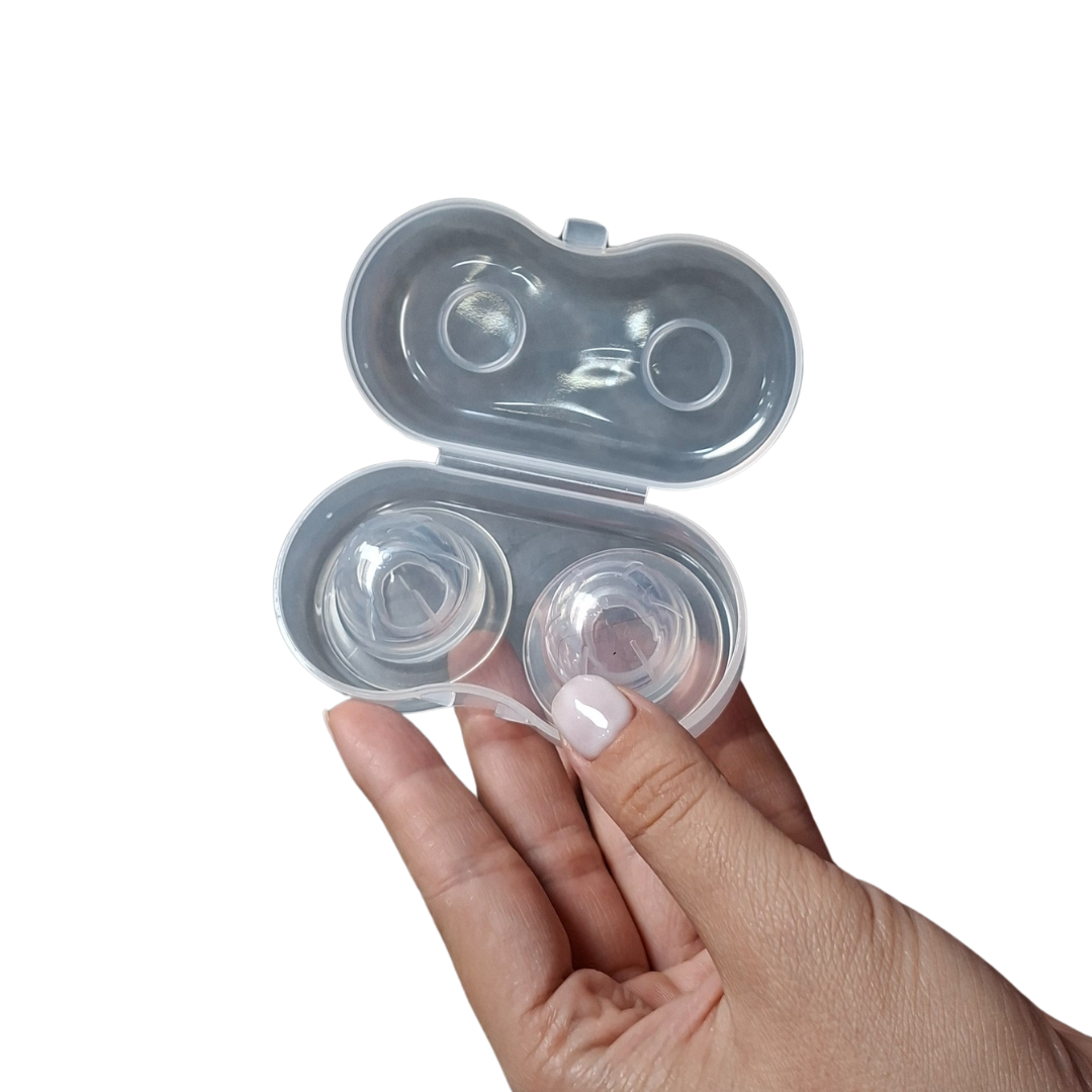 Manos sosteniendo dos saca pezones de silicona transparentes en un estuche, diseñados para corregir pezones planos o invertidos de forma discreta y cómoda.