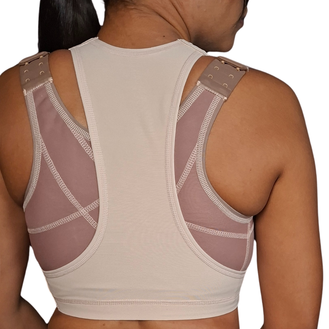 Mujer modelando un separador de senos postquirúrgico de color beige, con un diseño anatómico en forma de "T" que se ajusta entre los bustos para mantener la separación natural después de una cirugía de implantes.