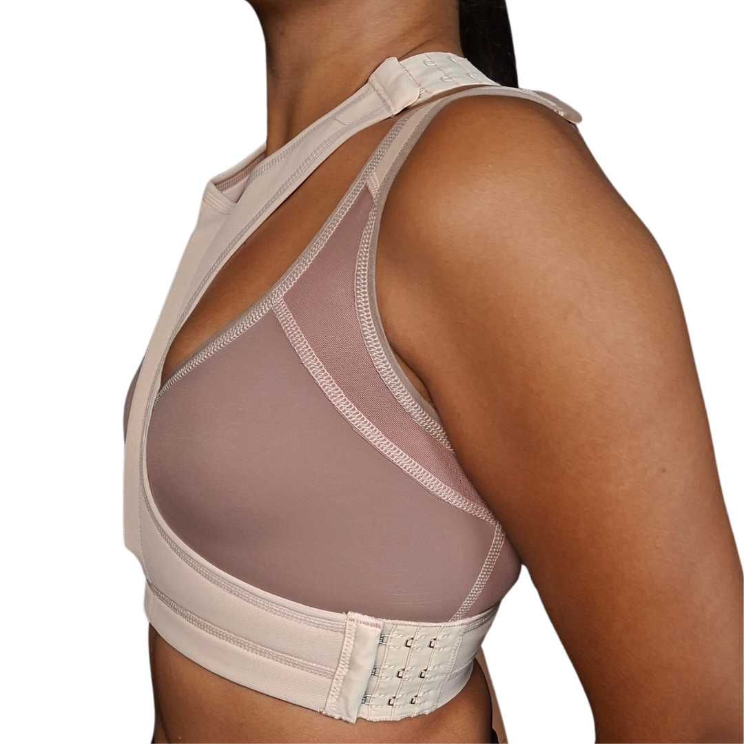 Mujer modelando un separador de senos postquirúrgico de color beige, con un diseño anatómico en forma de "T" que se ajusta entre los bustos para mantener la separación natural después de una cirugía de implantes.