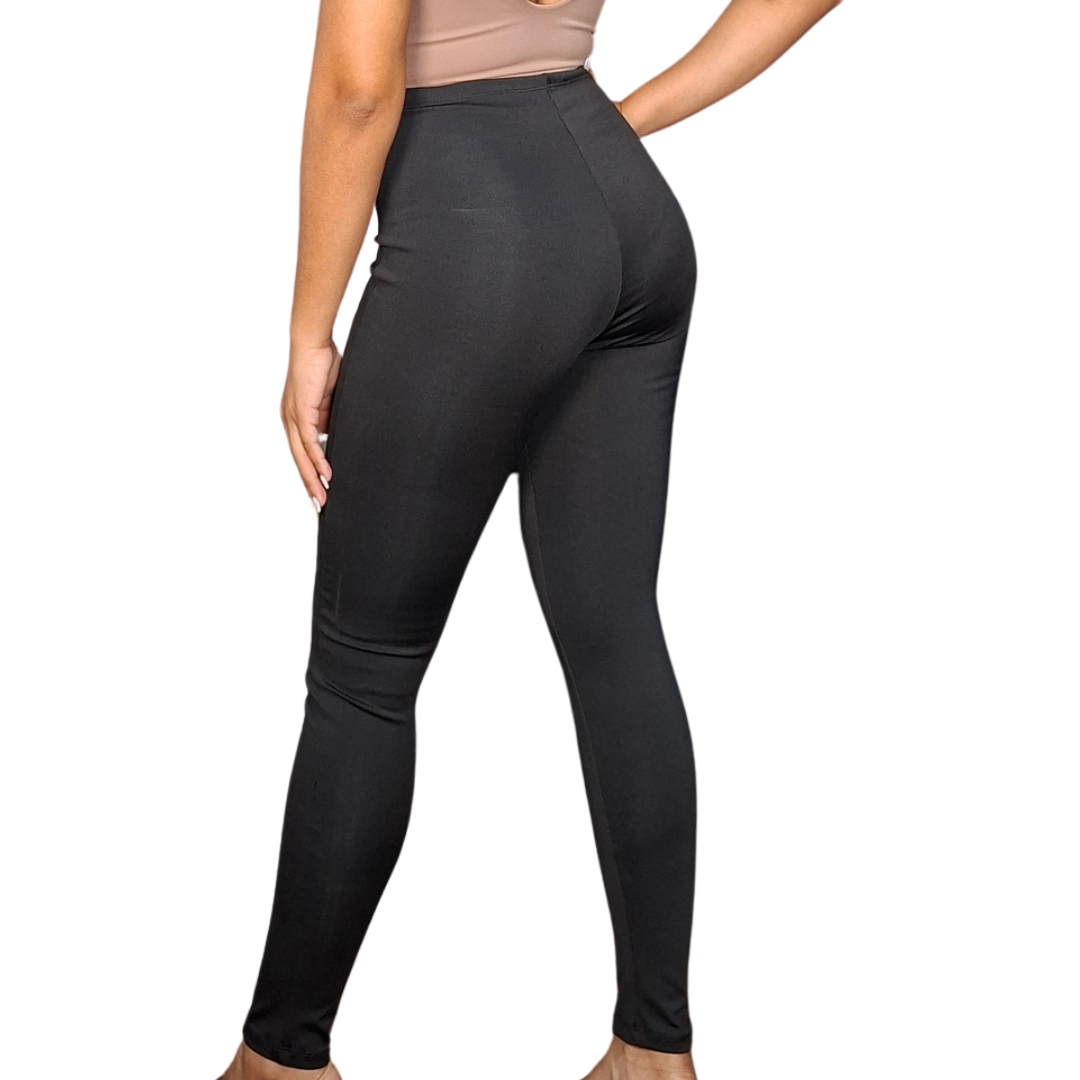 Mujer luciendo un pantalón negro exterior de corte skinny (ajustado), con pretina alta que integra una faja interna de alta compresión para aplanar el abdomen.