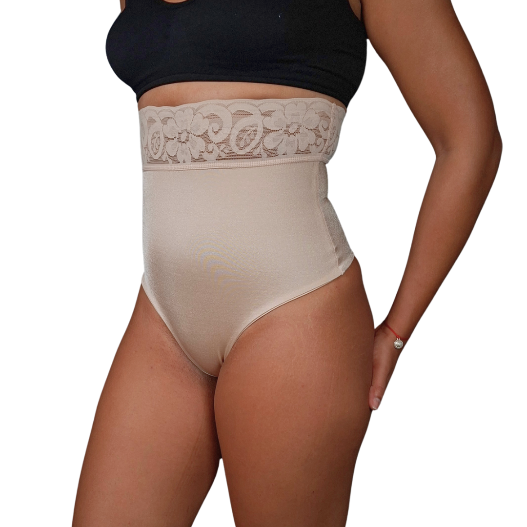 Vista frontal de tres cuartos de una mujer utilizando un panty faja de corte hilo en tono beige de talle alto, finalizado con una banda ancha de encaje floral en la parte superior.