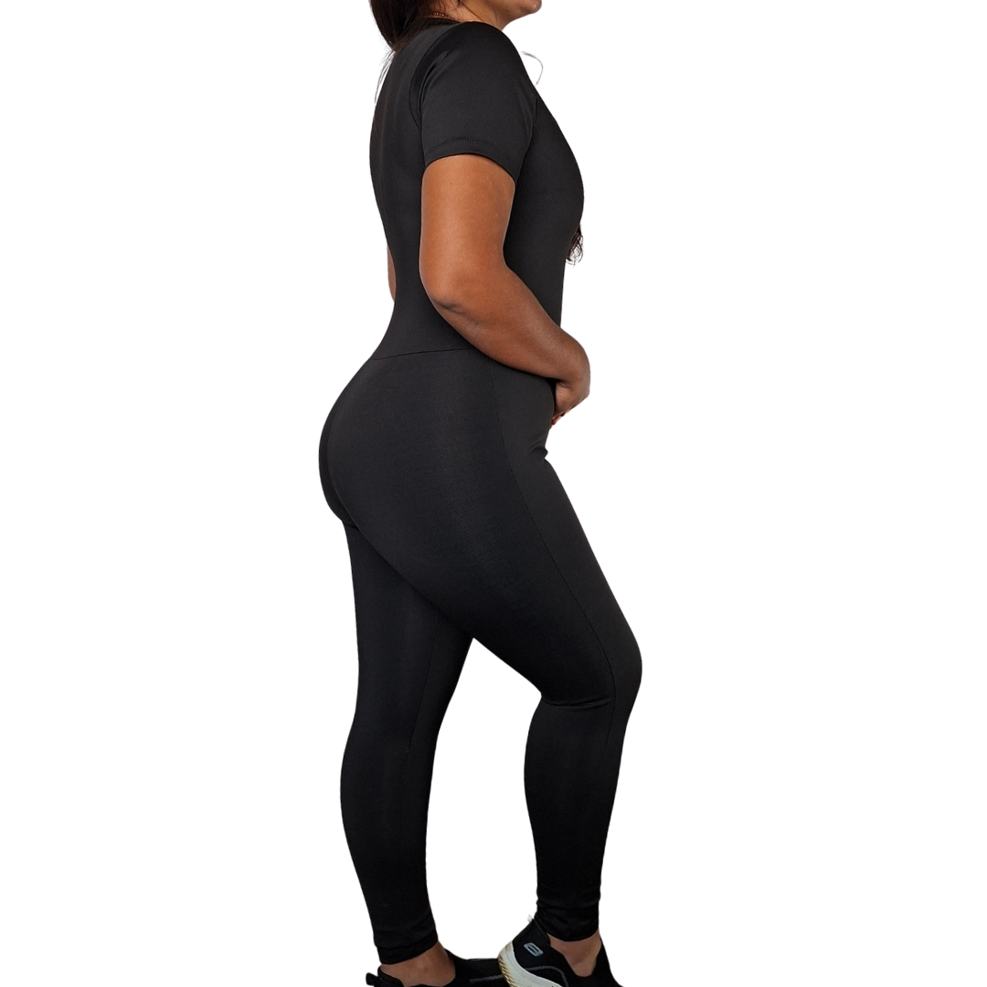 Vista de perfil de una mujer luciendo un enterizo exterior negro de manga corta y bota ajustada tipo legging, destacando la definición de la silueta en cintura y glúteos.